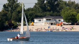 Ein Segelboote auf dem Liblarer See, im Hintergrund das Strandbad
