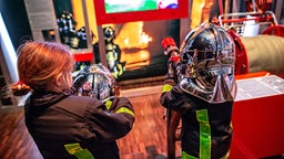Zwei Kinder spielen in der DASA-Ausstellung Feuerwehrleute.