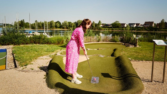 Eine Frau spielt Minigolf im Freizeitpark Xanten