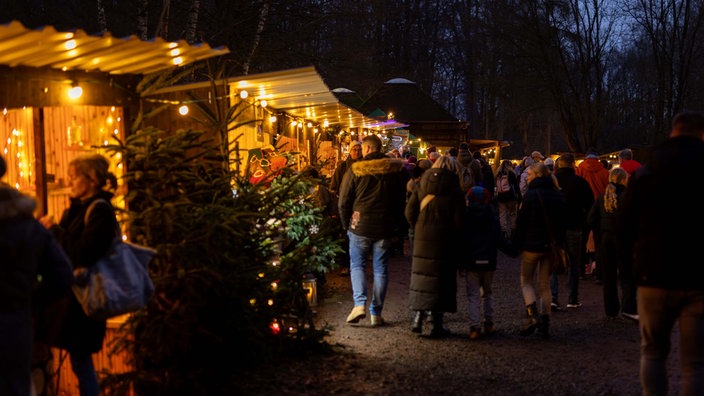 Weihnachtsmarkt-Besucher gehen an Buden auf dem Waldmarkt im Wildwald Vosswinkel vorbei