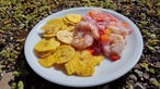 Ceviche de Camarones mit Chifles auf einem weißen Teller angerichtet