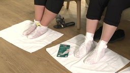 Zwei Personen tragen eine Fußmaske.