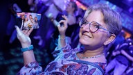 Eine Besucherin bei WDR 2 Hausparty in Siegburg hält fröhlich ihre Eintrittskarte in die Höhe