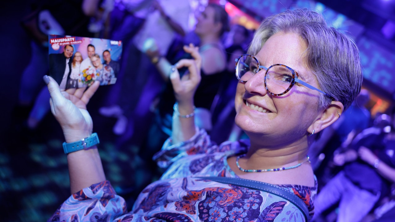 Eine Besucherin bei WDR 2 Hausparty in Siegburg hält fröhlich ihre Eintrittskarte in die Höhe