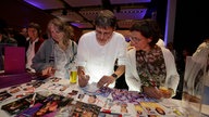 Menschen füllen Quizkarten aus bei der WDR 2 Hausparty in Siegburg