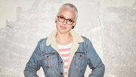 Die Sängerin Stefanie Heinzmann steht vor einer grauen Betonwand, hat die Hände in den Jackentaschen 