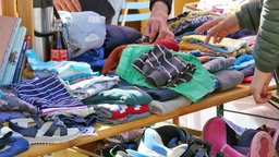 An einem Flohmarkt-Stand liegen Klamotten und Schuhe aus.