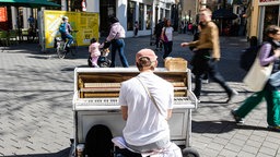 Ein Straßenmusiker spielt in der Bonner Innenstadt auf einem Klavier.
