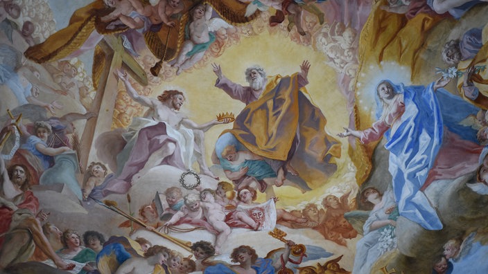 Das Barocke Deckengemälde unter der Kuppel der Basilika in Weingarten zeigt, wie Jesus Christus vom Kreuz steigt und in den Himmel aufsteigt. Die Szene ist umringt von Putten und Engeln.