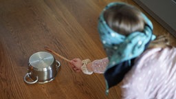 Ein Kind spielt bei einem Kindergeburtstag Topfschlagen mit verbundenen Augen. 