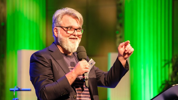 Aufnahme von der Gala des Klassik Forums im Kölner Funkhaus: WDR 3 Klassik Forum-Moderator Jörg Lengersdorf mit einem Mirkofon.