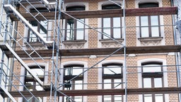 Eine historische Hausfassade hinter einem Baugerüst in Köln.