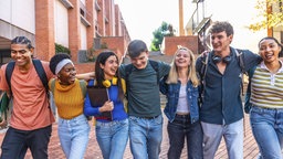 Eine Gruppe junger Menschen, die Arm in Arm zusammen lachen.