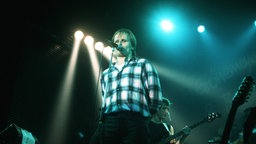 Eine Bühnenaufnahme des singenden Herbert Grönemeyer im Scheinwerferlicht aus dem Jahr 1984.