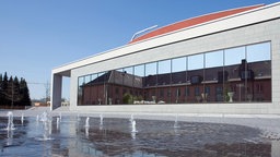 Das Konzert Theater Coesfeld spiegelt sich in einer Wasserpfütze.
