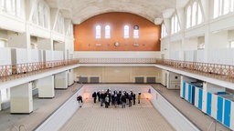 Archivaufnahme von 2019: Innenansicht des Krefeldes Stadtbads, in dessen leerem Schwimmbecken ein Menschengruppe steht.