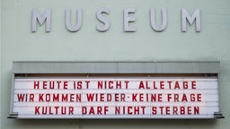 Ein Schild mit der Aufschrift "Heute ist nicht alle Tage: Wir kommen wieder. Keine Frage, Kultur darf nicht sterben" hängt unter dem Schriftzug "Museum".