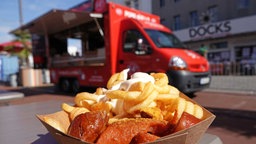  Eine Portion Currywurst mit Pommes ist vor einem Foodtruck zu sehen