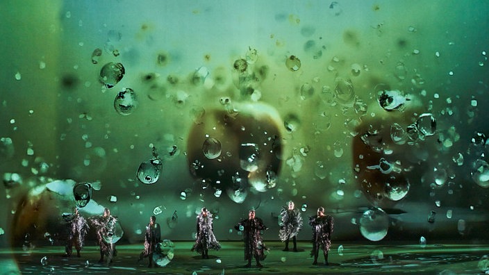 Szenenfoto: "Das Rheingold" bei den Bayreuther Festpielen mit KI-Bühnenbild und großflächigen Projektionen von Wassertropfen.