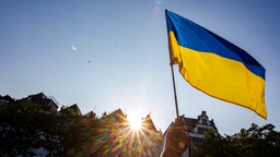 Ein Teilnehmer hält bei einer Kundgebung des Vereins Blau-Gelbes Kreuz zum Unabhängigkeitstag der Ukraine eine ukrainische Flagge. 