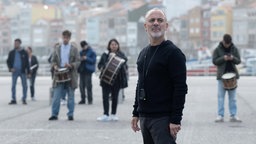 Filmstill von "So klingt das Leben": Hauptdarsteller Javier Gutiérrez im Vordergrund, im Hintergrund vereinzelte Menschen mit Trommeln.