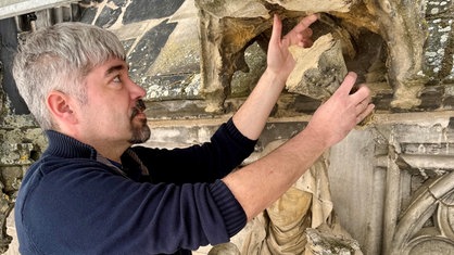 Ein Mann steht auf einem Gerüst am Aachener Dom