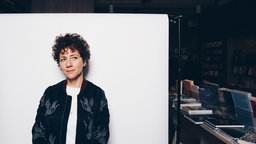 Sasha Marianna Salzmann posiert vor einer weißen Wand in der Buchhandlung InterKontinental in Berlin, 2022.