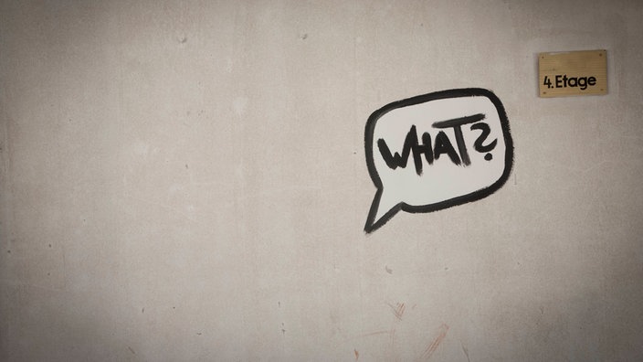 Das Graffito einer Sprechblase mit der Inschrift "What?" an einer Wand.