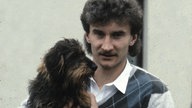 Rudi Völler 1983 mit lockigem Vokuhila, Oberlippenbart und einem Dackel auf dem Arm