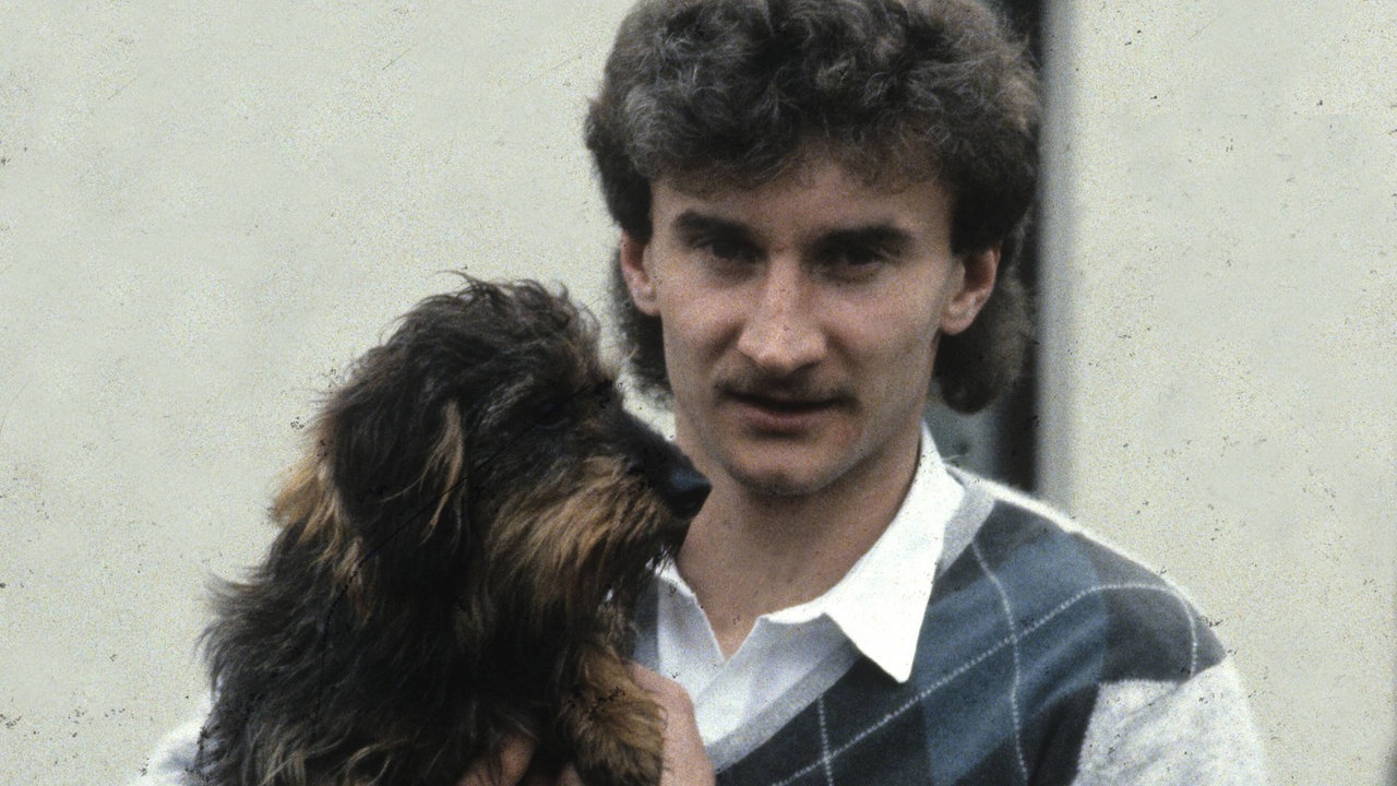 Rudi Völler 1983 mit lockigem Vokuhila, Oberlippenbart und einem Dackel auf dem Arm