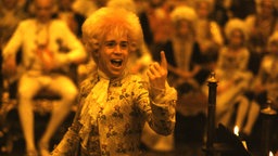 Filmszene aus "Amadeus" (1984): Tom Hulce als Wolfgang Amadeus Mozart mit erhobenem Zeigefinger im Kerzenschein