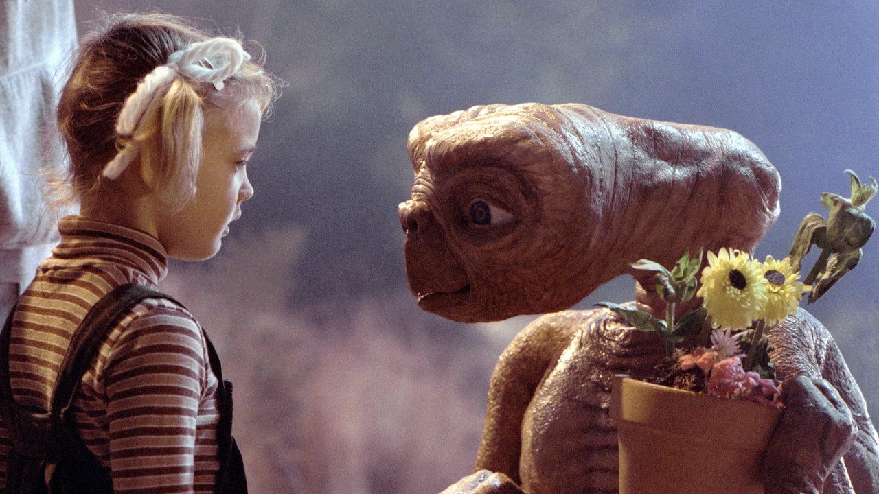 Filmszene aus "E.T.": Der gleichnamige Außerirdische hält einen Blumentopf in der Hand und steht einem kleinen Mädchen gegenüber