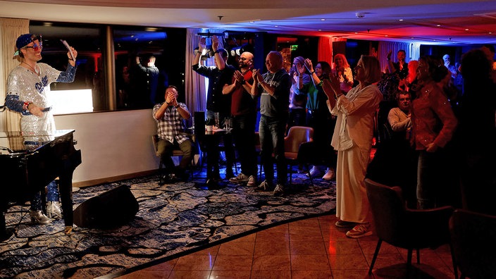 Musiker mit Glitzeroutfit nimmt Applaus der Publikums entgegen