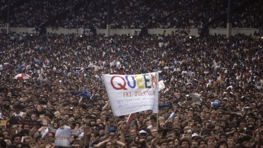 Queen Live at Wembley Stadium, 11th July 1986, Blick in die Masse, die ein Transparent mit der Aufschrift "Queen" hochhält