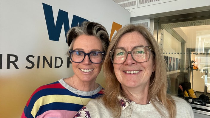 Ein Selfie von Ildikó von Kürthy und Ute Schneider im WDR 4 Studio. Beide läscheln freundlich in die Kamera. Ildikó von Kürthy trägt einen farbenfroh gestreiften Pulli, Ute Schneider einen beigen Pullunder, darunter eine weiße Bluse mit lila Blumen.