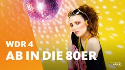 Eine im Stil der 80er Jahre gekleidete Frau mit Sonnenbrille, wilden Haaren, Kette, Schweißband und Kopfhörer schaut in die Kamera. Im Hintergrund dreht sich eine Discokugel