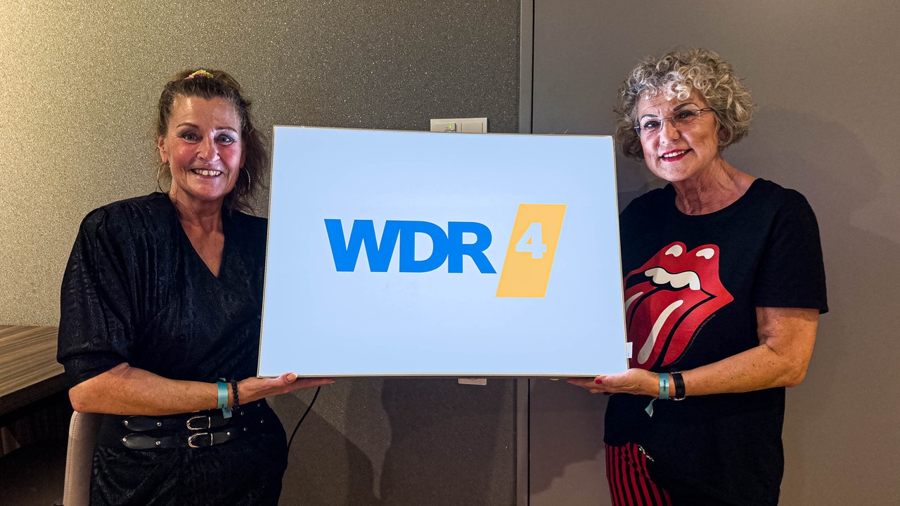 Zwei WDR 4 Hörerinnen halten ein Schild mit der Aufschrift "WDR4" hoch