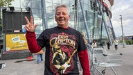 Ein Fan von Eric Clapton trägt ein Fanshirt und zeigt den erhobenen Daumen