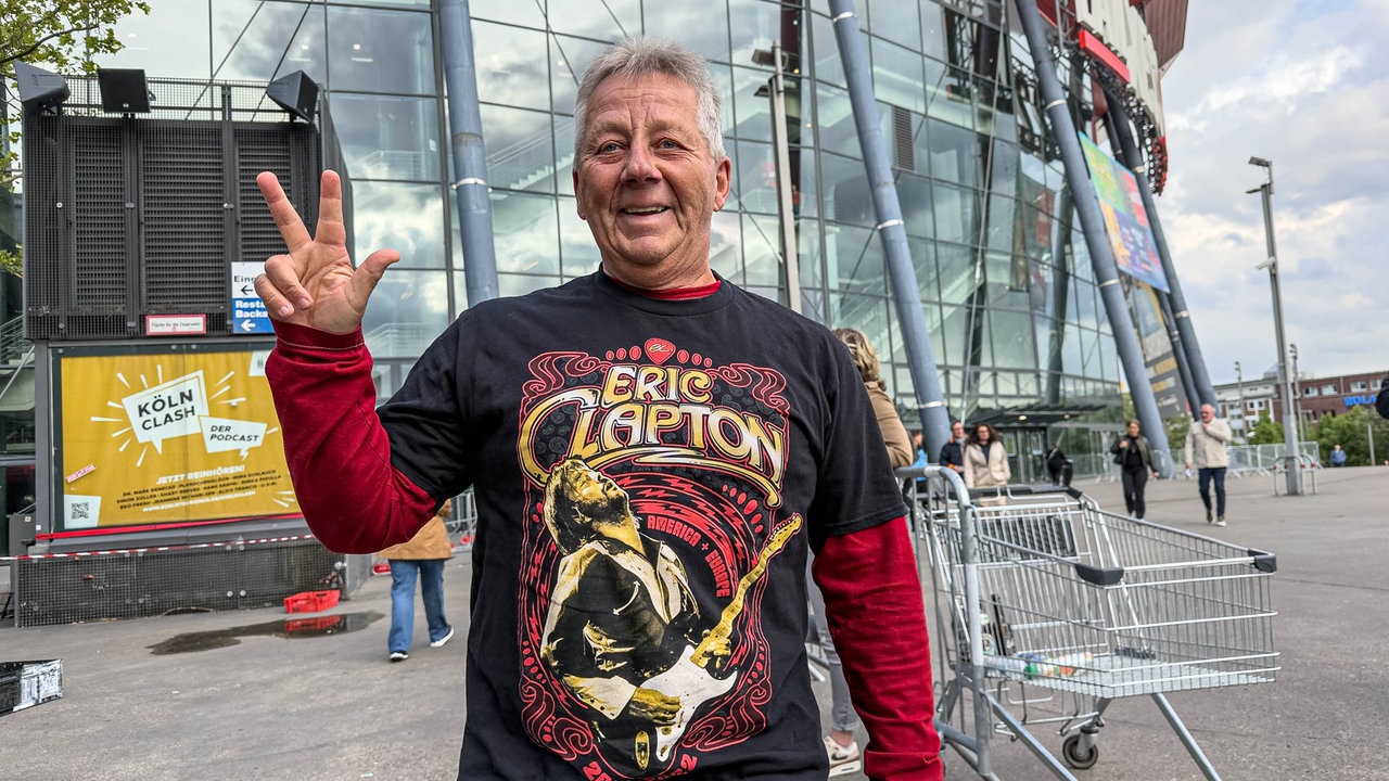 Ein Fan von Eric Clapton trägt ein Fanshirt und zeigt den erhobenen Daumen