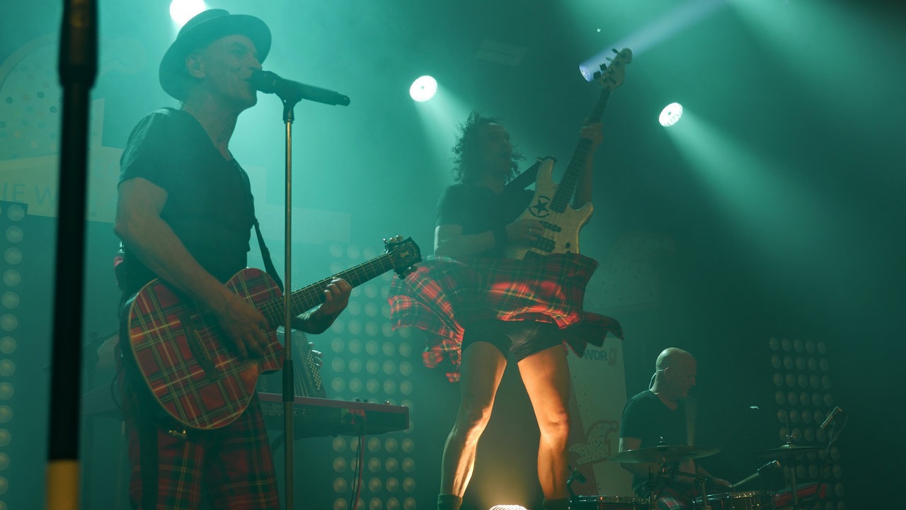 Zwei Musiker von Brings, einer davon mit hochgewehtem Schottenrock
