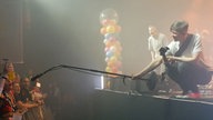 Der Bassist von Kasalla hält ein Mikro ins Publikum