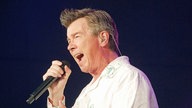 Rick Astley singt ins Mikro