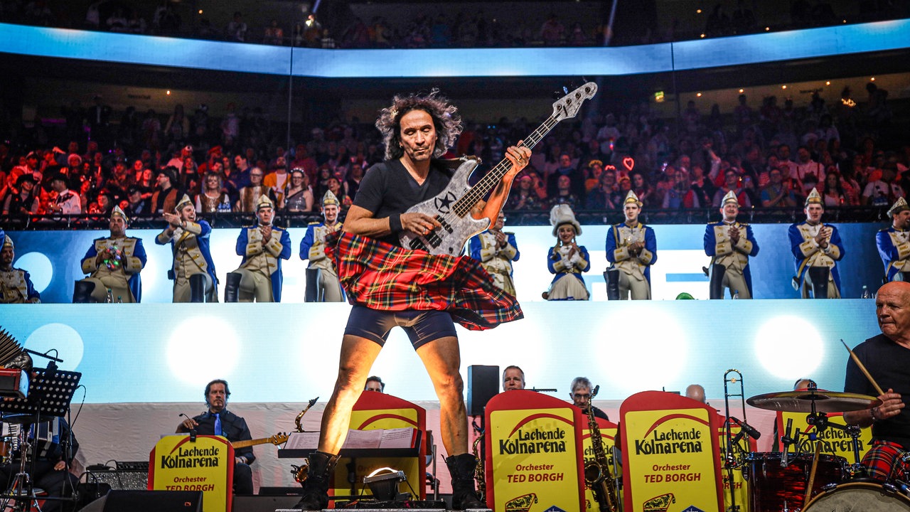 Lachende Köln Arena 2026: Gitarrist Stephan Brings spielt über einer Lüftung. Sein roter Schottenrock fliegt dadurch nach oben durch die Luft