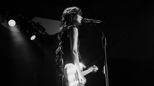 Nena steht mit einer Gitarre auf der Bühne und singt in ein Mikrofon