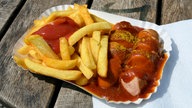 Currywurst mit Pommes in einer Pappschale
