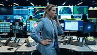 Szene aus dem Film "A House of Dynamite": Rebecca Ferguson als Captain Olivia Walker steht telefonierend in einem Kontrollraum, umgeben von Bildschirmen. Sie sieht ernst aus und hat eine Hand an die Hüfte gestemmt.