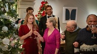 Eine Szene des Films "A Merry Little Ex-Mas": Die Familie steht festlich gekleidet im weihnachtlichen geschmückten Wohnzimmer und stößt mit Sekt an. 