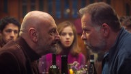 Szene aus dem Film "Familie, aber nur fast": Schauspieler Gabriel Goity und Leandro Hassum stehen sich wütend gegenüber, während ein junges Paar im Hintergrund sie geschockt anschaut