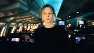 Szene aus dem Film "Flightplan – Ohne jede Spur": Schauspielerin Jodie Foster steht im Mittelgang eines spärlich beleuchteten Flugzeuges