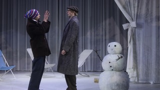 Zwei Männer und ein Schneemann auf einer Bühne